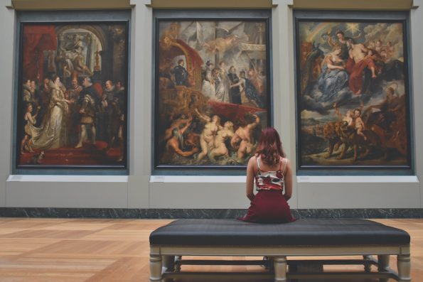 A woman looking at paintings in a gallery.